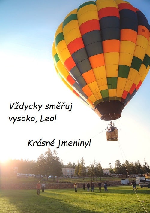 Barevný létající balón, vzlétající z louky, s přáním krásných jmenin Leovi.