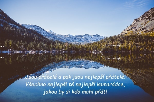 Horské jezero obklopeno zalesněnými a zasněženými kopci se svátečním přáníčkem Romaně. 