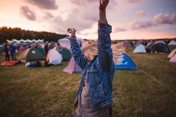 Radostně tancující dívka na louce se stany