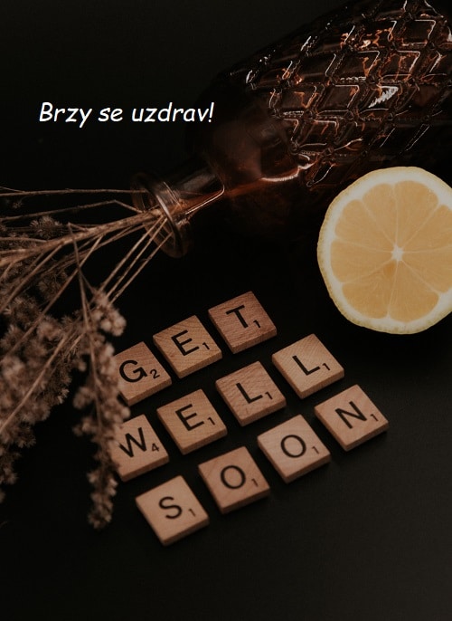 Převrácená váza se suchými květinami, citronem a dřevěnými kostičkami s anglickým nápisem "Get well soon" a s přáním brzkého uzdravení.